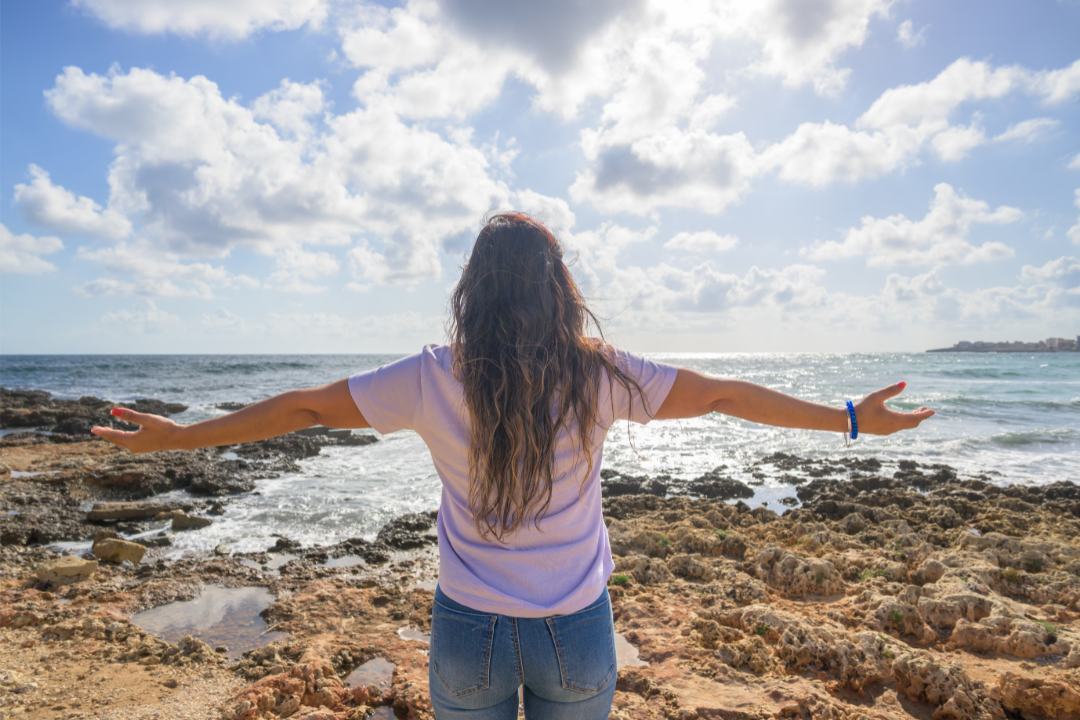 Arms open facing the ocean